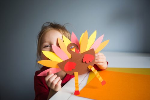 Child holding a colorful paper turkey craft, symbolizing creativity and communication skills supported through speech and language therapy in NYC.