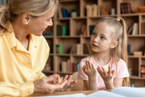 Smart caucasian girl preschooler learing to count with her mother helping, sitting at desk in living room and studying. Mom helping her daughter learning numbers