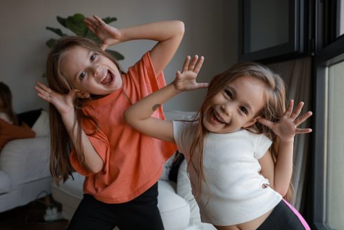 Close up of two beautiful little girl at living room and laughing.
