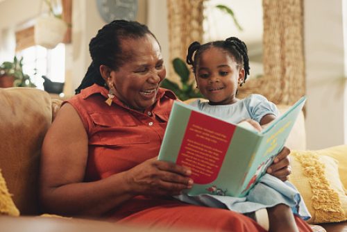 A grandmother and granddaughter enjoy a colorful storybook together, creating connection and learning at bedtime. Speech therapy in NYC encourages shared reading to boost children’s language growth.