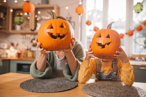 Mother and daughter scooping a Carved pumpkin. Making Jack o Lantern at home kitchen.
