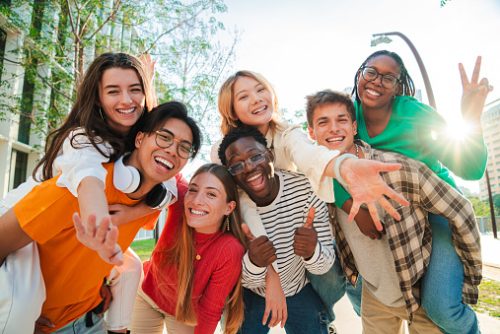 Big group of multiracial young student people smiling, gesturing and looking at camera. Happy internacional teenagers laughing. Cheerful friends enjoying their freedom. Classmates on friendly meeting. High quality photo