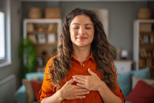 Woman practicing mindful breathing with hands on her chest, representing grounding techniques often integrated into speech and language therapy in NYC.