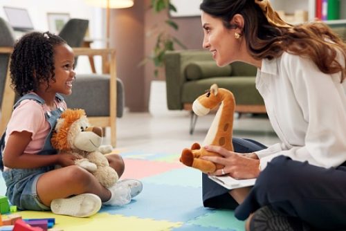 Psychology, woman and girl with dolls, talk and happy with clipboard for emotional assessment on floor. Person, therapist and child with toys, playful and checklist for test at mental health clinic