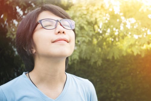 Child with glasses enjoying a mindful breathing moment in nature, representing how a speech therapist in NYC blends mindfulness with speech therapy to help kids who struggle to focus.