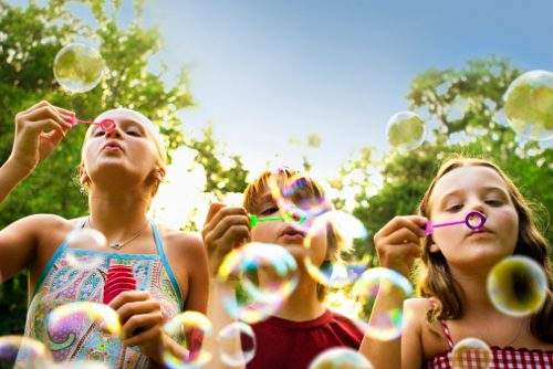 Children blowing bubbles outdoors.