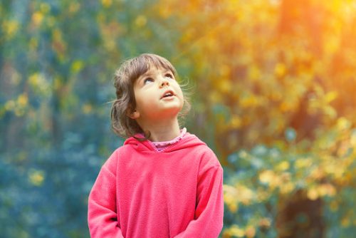 Child looking upward while outdoors, symbolizing presence, curiosity, and engagement fostered through neurodiverse affirming speech therapy in NYC.